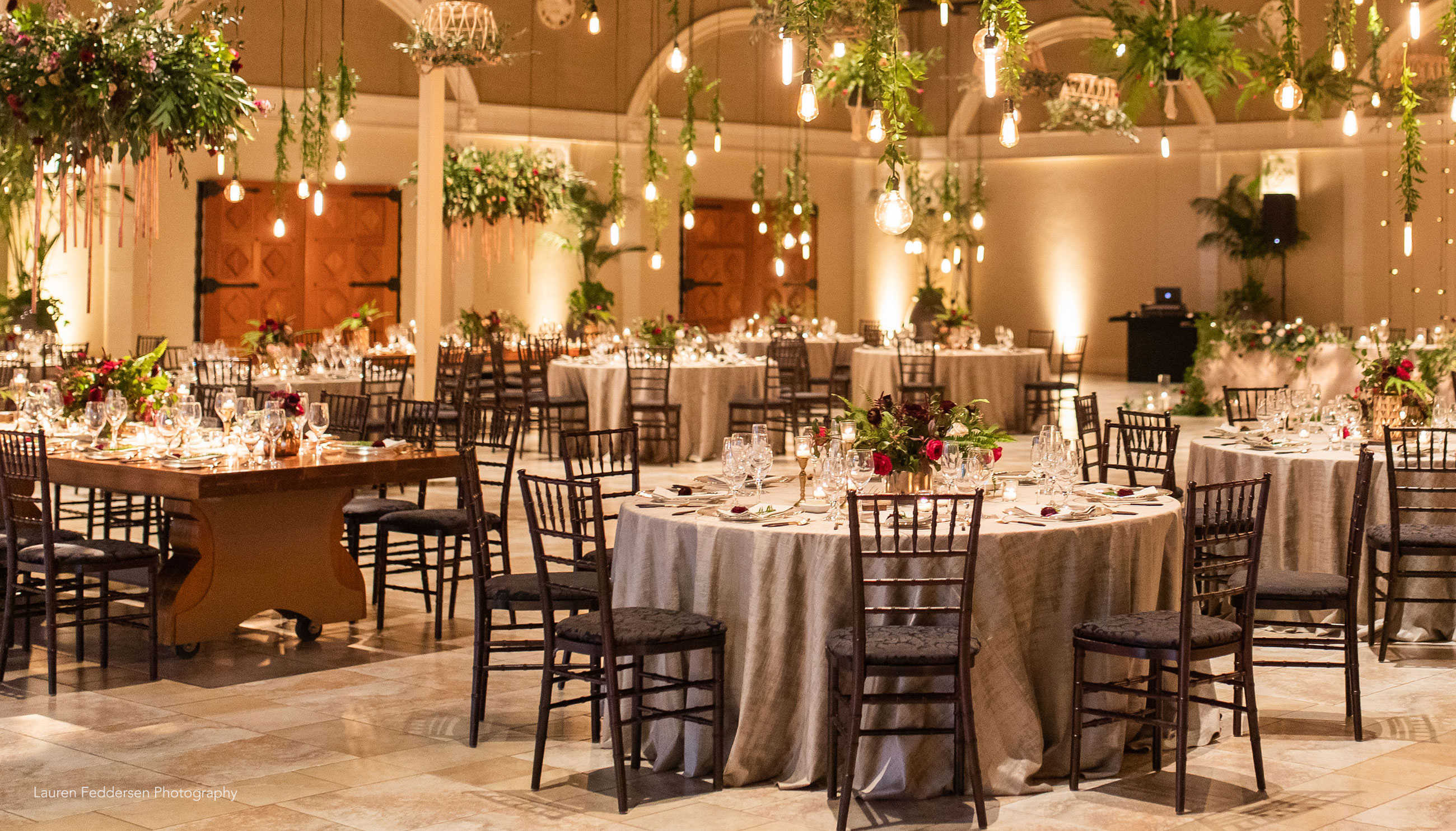 Unique boho wedding reception with hanging greenery and Edison light bulbs at Casa Real at Ruby Hill Winery (www.casarealevents.com).  Photo by: Lauren Feddersen Photography; Florals (and floral chandelier): Nicole Ha Design; Lighting: Fantasy Sound Event Services; Linen: Pleasanton Rentals